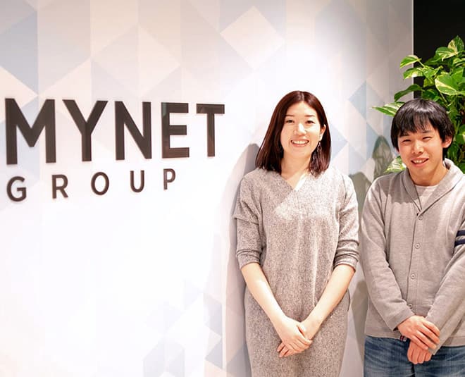 Picture of a male and female mynet group employees with the company name in the background